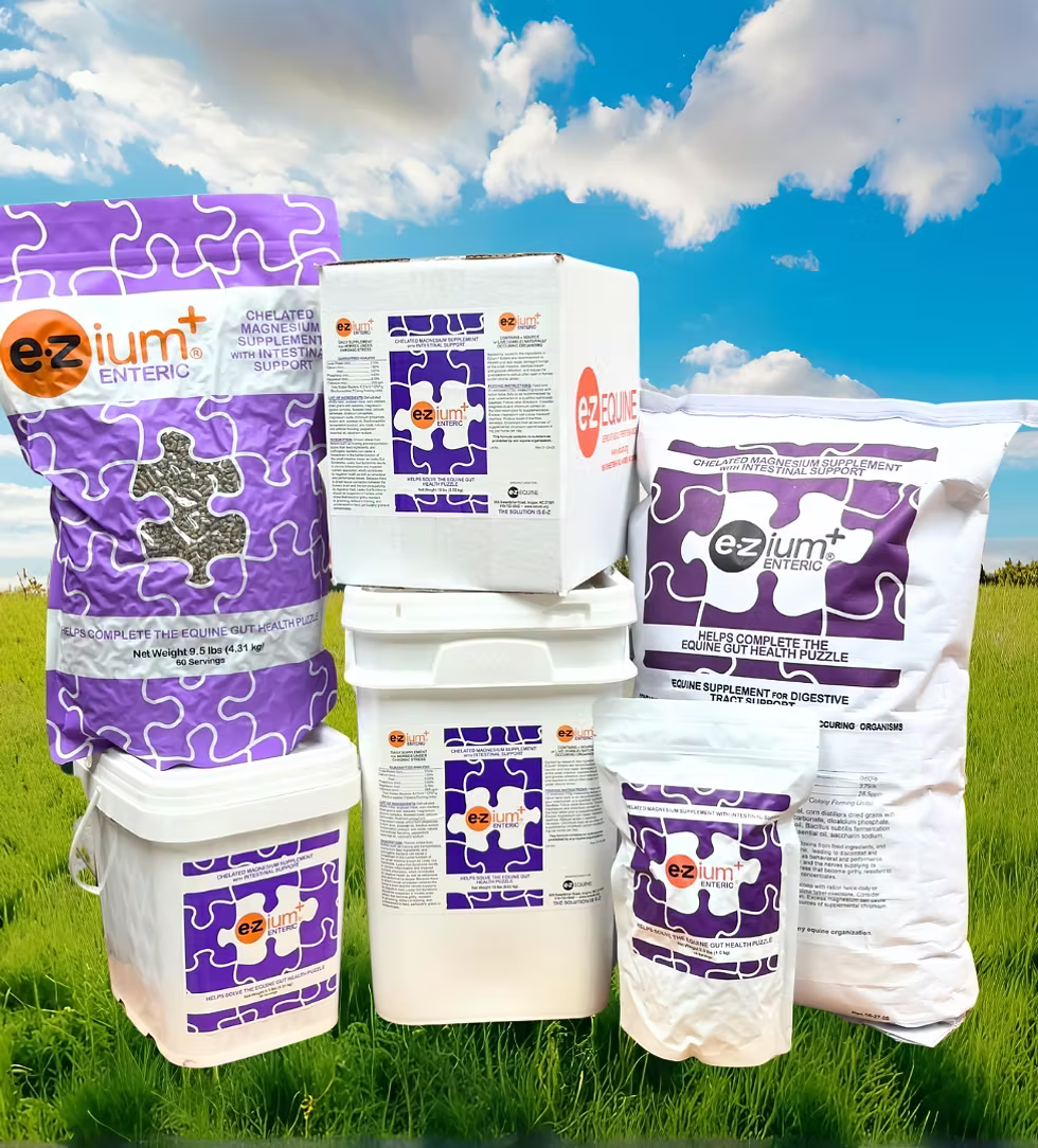 Collection of ezium+ Enteric products on a grassy field with a blue sky.
